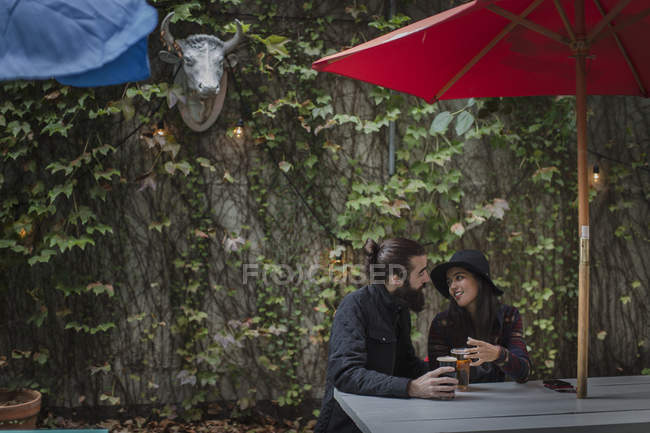 Jeune couple bavardant dans un jardin de bière le soir, Brooklyn, New York, USA — Photo de stock
