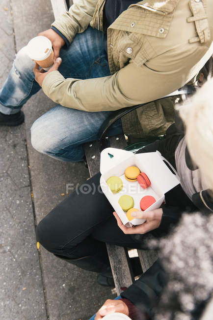 Cropped view of friends holding box of macaroons — Stock Photo