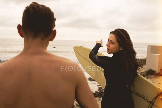 Due amici che camminano verso il mare, portando tavole da surf, vista posteriore — Foto stock