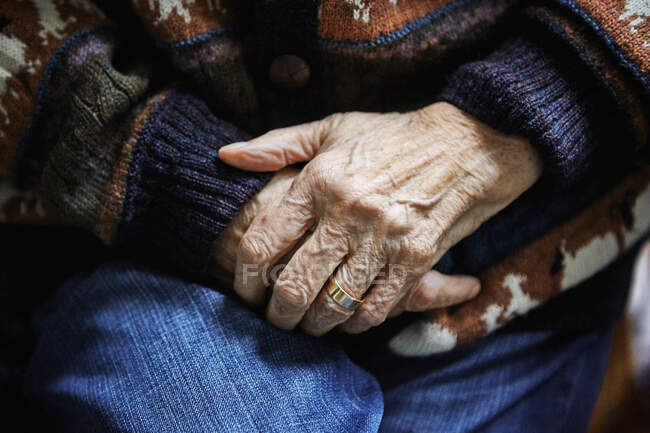 Senior mulher sentada na cadeira, mãos apertadas, close-up — Fotografia de Stock