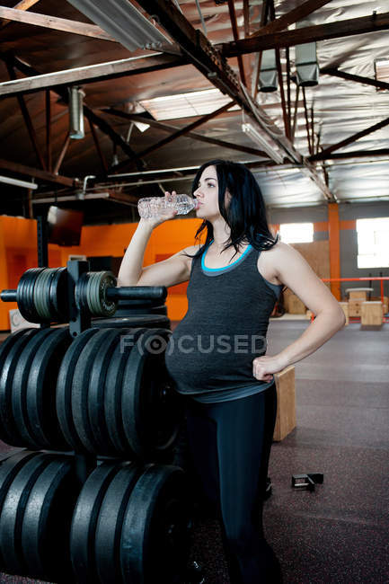 Mujer joven embarazada bebiendo agua mineral - foto de stock