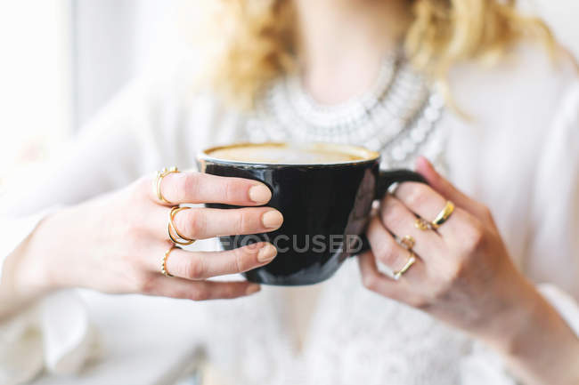 Mani che tengono la tazza nera di caffè — Foto stock