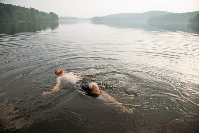 Hombre adulto medio nadando en el lago - foto de stock