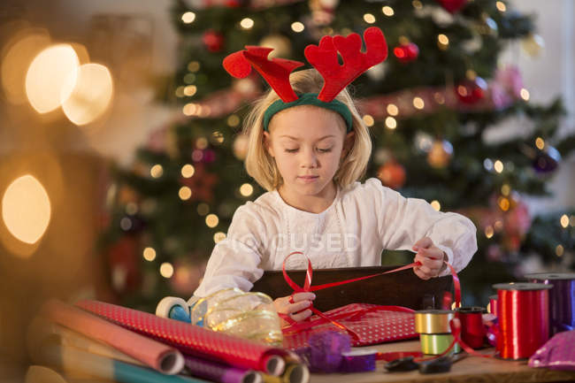 Fille enveloppant cadeaux de Noël à la maison — Photo de stock