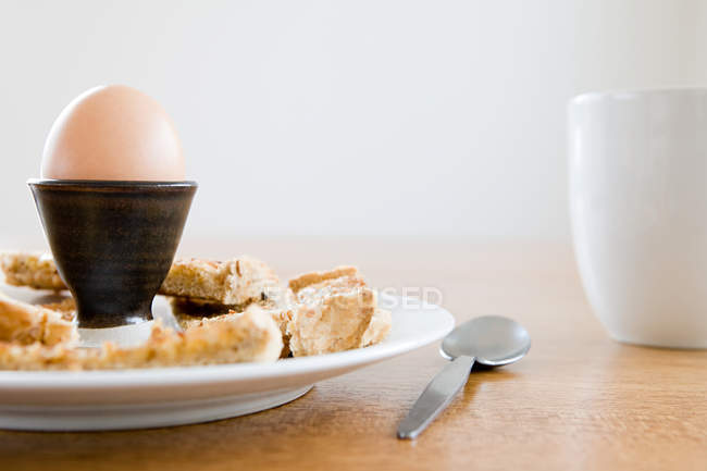 Egg in eggstand with bread on plate — Stock Photo