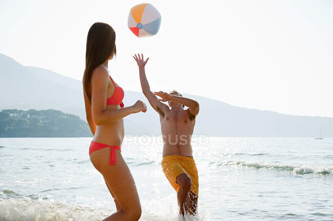 Jovem casal jogando com bola de praia na praia — Fotografia de Stock