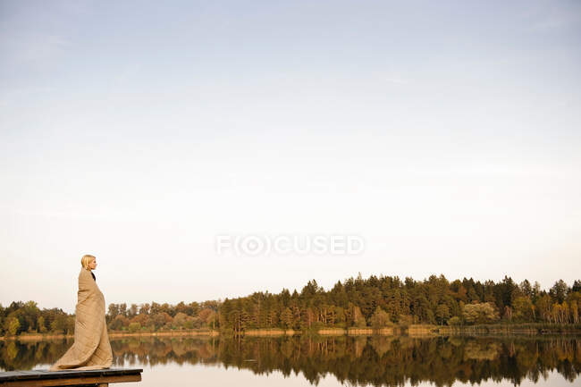 Молодая женщина, стоящая на пристани, наслаждаясь — стоковое фото