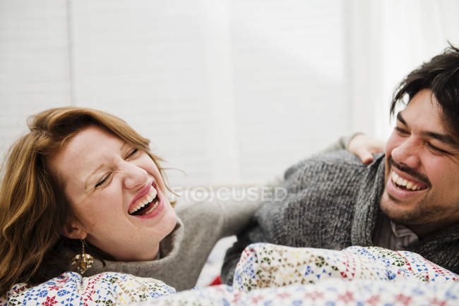 Couple riant ensemble sur le lit — Photo de stock