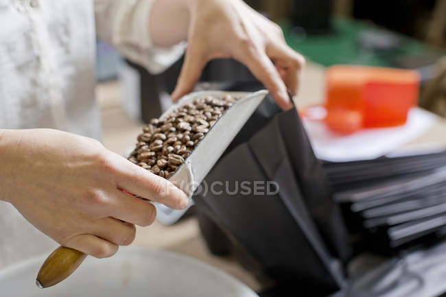 Bolso de llenado vendedor de café con granos de café - foto de stock