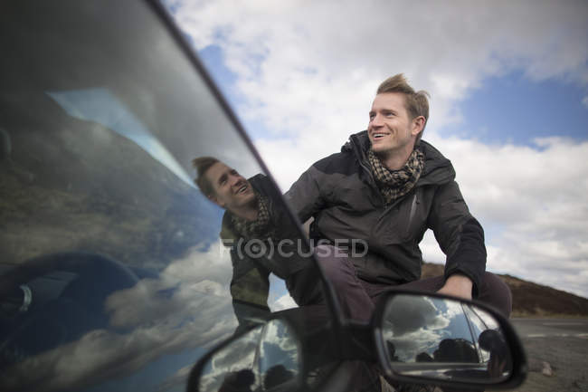 Середній дорослий чоловік на машині дивиться геть, посміхаючись — стокове фото