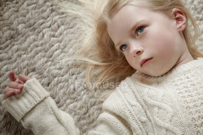 Giovane ragazza sdraiata sul tappeto — Foto stock