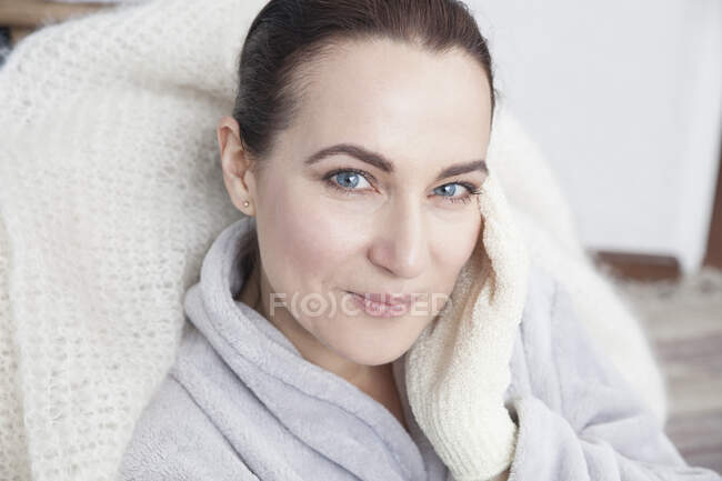 Mulher madura tocando o rosto com luva de esfoliação — Fotografia de Stock