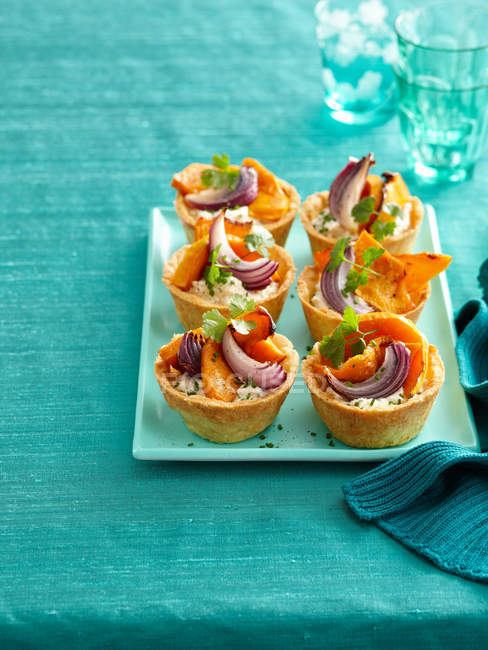 Plate of baked vegetable tarts served on table — Stock Photo