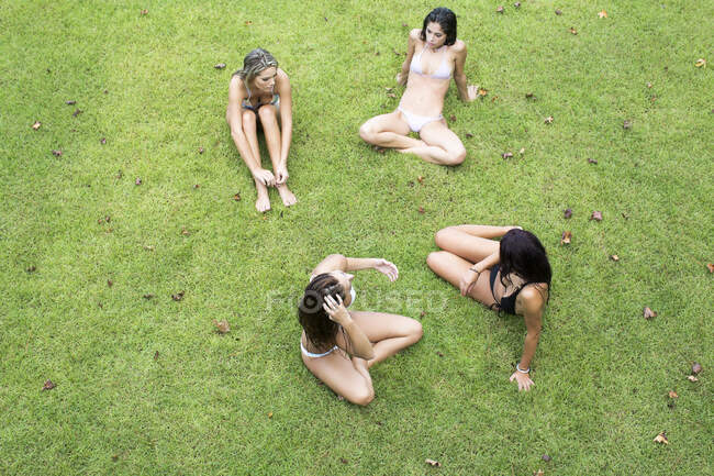 Overhead view of four women in bikinis sitting on lawn, Santa Rosa Beach, Florida, USA — Stock Photo
