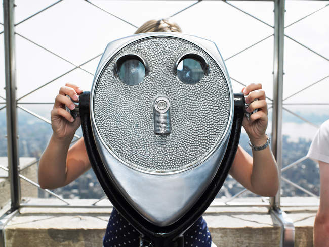Frontansicht einer jungen Frau, die durch ein Fernglas blickt — Stockfoto