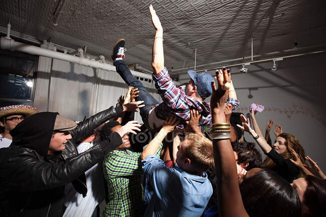 Man crowd surfing at party — Stock Photo
