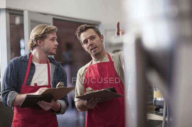 Cape Town, South Africa, male instructing co worker in brewery room — Stock Photo