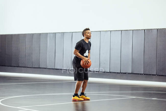 Male basketball player poised with ball on basketball court — Stock Photo
