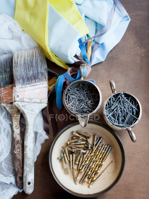 Прикраси пензлів, текстилю і цвяхів на столі — стокове фото