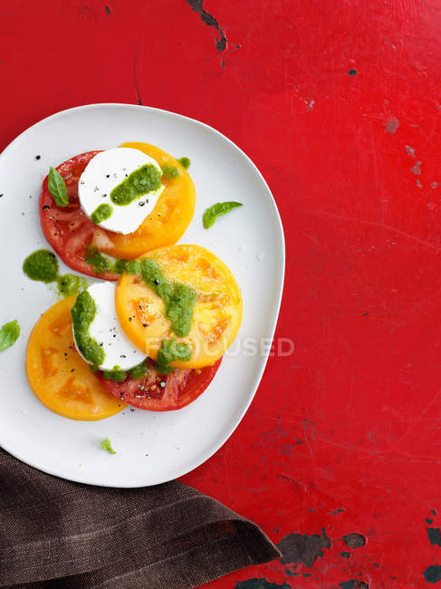 Plate of caprese salad on red rustic surface — Stock Photo