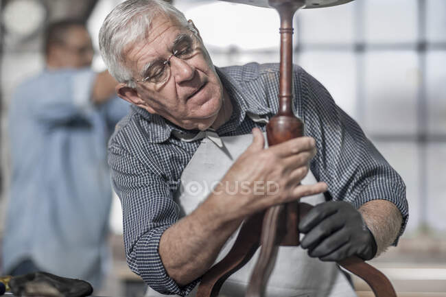 Cape Town, South Africa, elderly craftsman adjusting wooden arm in workshop — Stock Photo