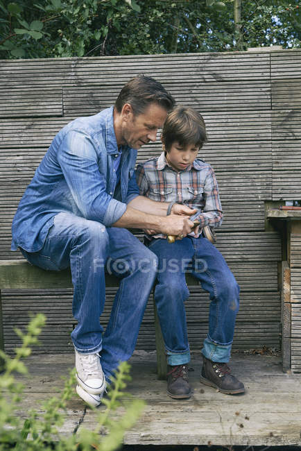Father showing son how to use pocket knife on allotment — Stock Photo
