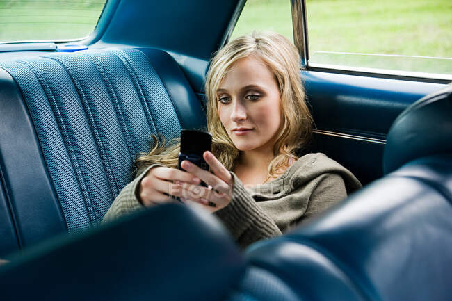 Молода жінка в машині з мобільним телефоном — стокове фото