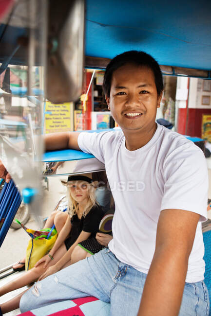Smiling pedicab driver with passengers — Stock Photo