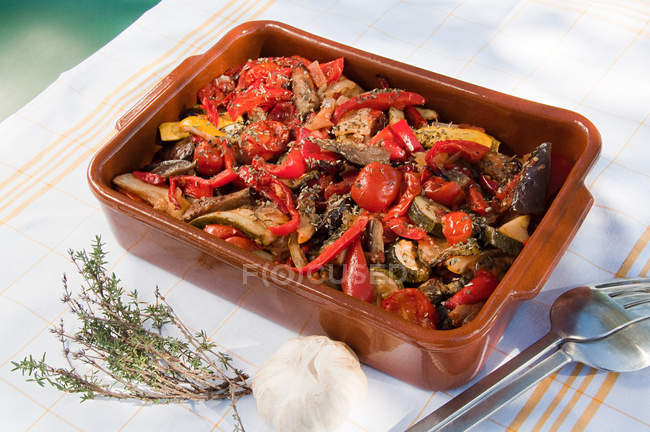 Ratatouille in ceramic dish with herbs and garlic on table — Stock Photo