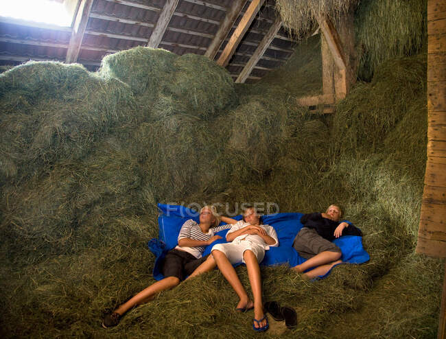 Meninas e menino dormindo no celeiro de feno — Fotografia de Stock