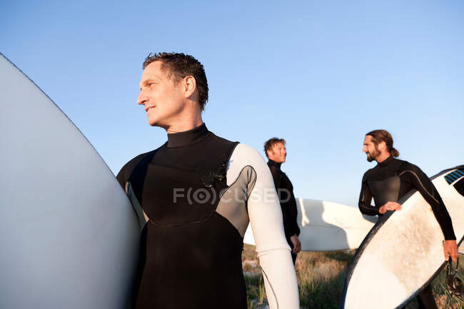 Tres surfistas en la playa - foto de stock