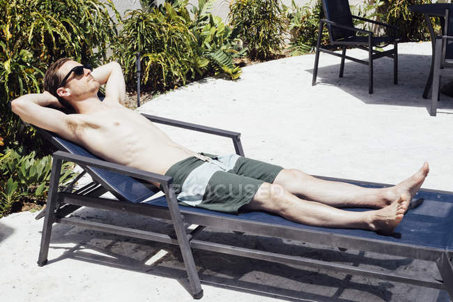 Homem adulto médio banhos de sol na espreguiçadeira, Miami Beach, Flórida, EUA — Fotografia de Stock