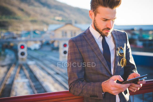 Молодой человек с цифровым планшетом на железнодорожном пешеходном мосту — стоковое фото