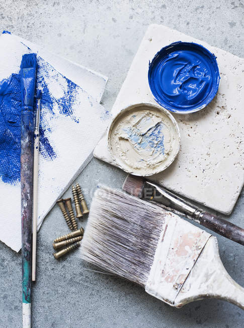 Paintbrushes and fresh paints on rustic surface — Stock Photo