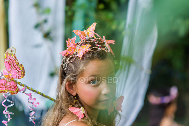Porträt eines jungen Mädchens, das Schmetterlinge im Haar trägt und einen Zauberstab hält — Stockfoto