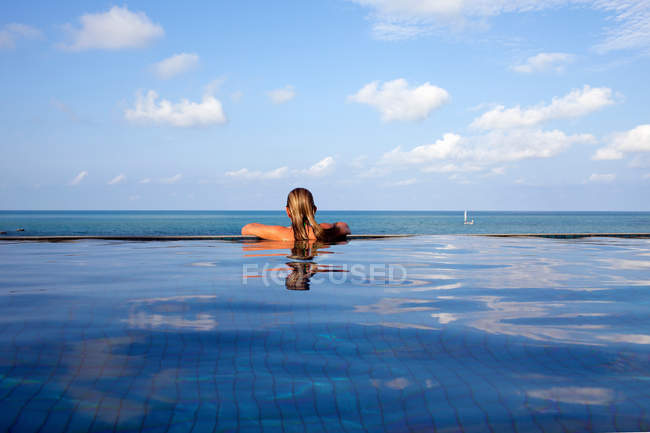 Back view of Woman relaxing in infinity pool — Stock Photo