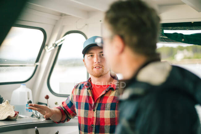Zwei Männer unterhalten sich auf einem Fischerboot an der Küste von Maine, USA — Stockfoto