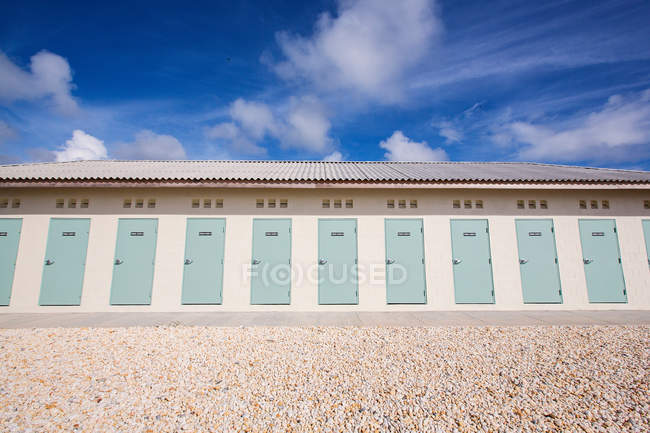 Portes du bâtiment sur la plage rocheuse avec ciel nuageux bleu — Photo de stock
