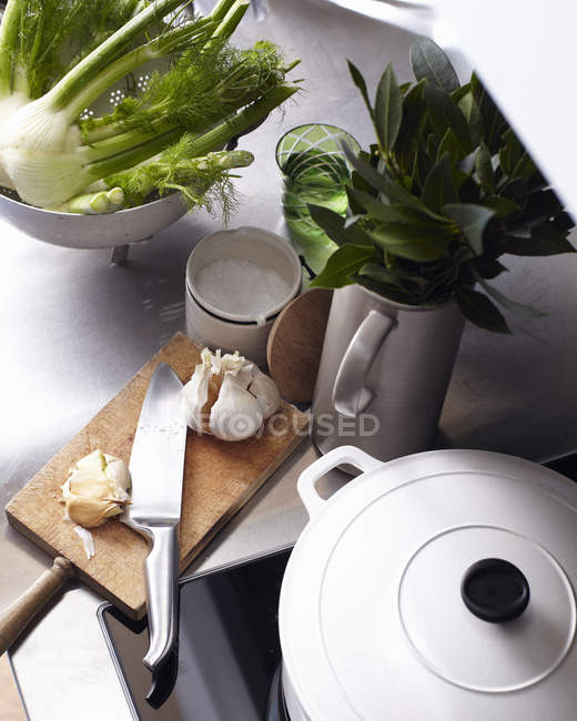 Comptoir et plaque de cuisson avec planche à découper et légumes — Photo de stock