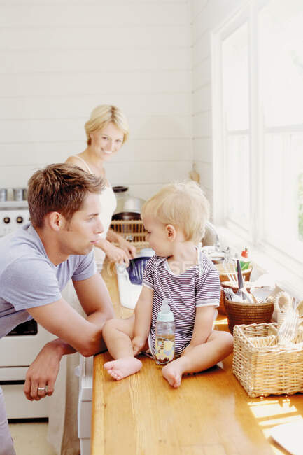 Padres jóvenes con niños en la cocina - foto de stock