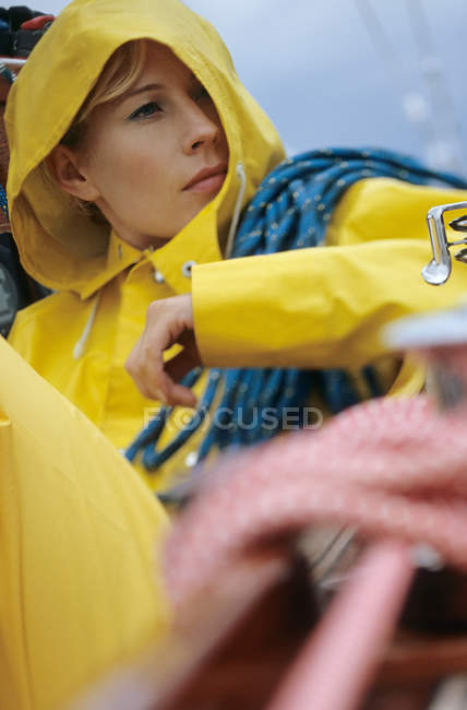 Woman in yellow raincoat carrying rope — Stock Photo
