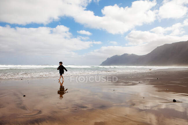 Chico corriendo en una playa - foto de stock