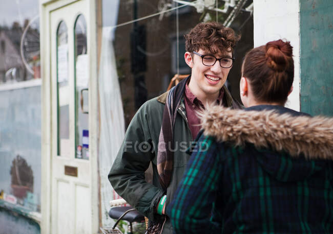 Молодая пара снаружи кафе, улыбающаяся — стоковое фото