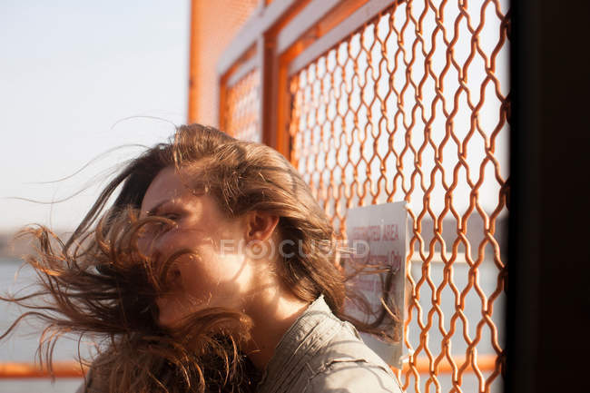 Giovane donna su un traghetto, vento che soffia capelli — Foto stock