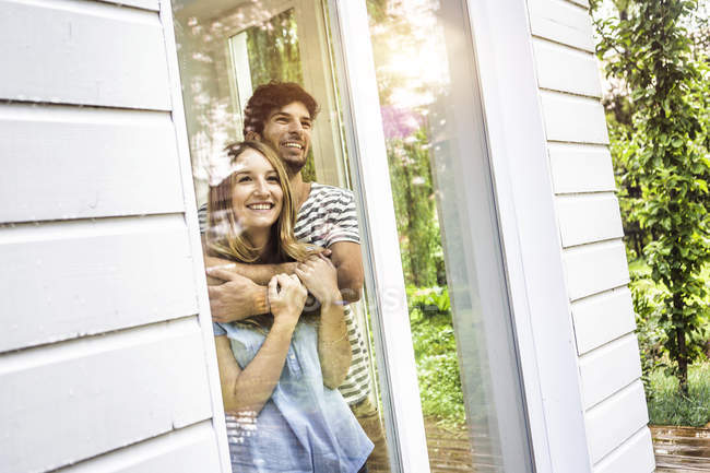 Jovem casal olhando para fora da janela do pátio — Fotografia de Stock