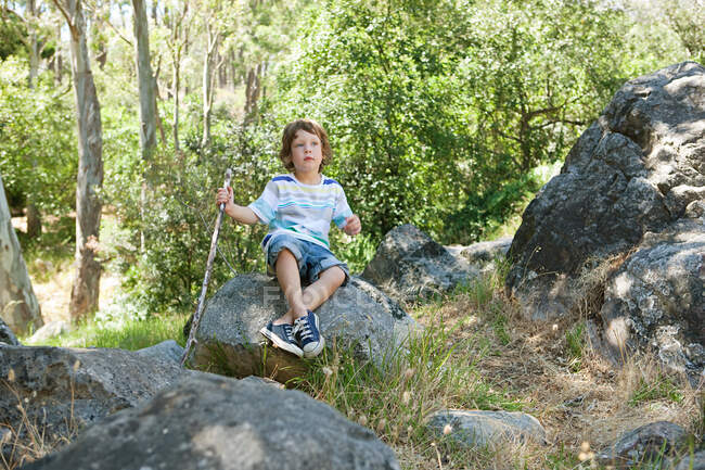 Ragazzo che si siede sulla roccia — Foto stock