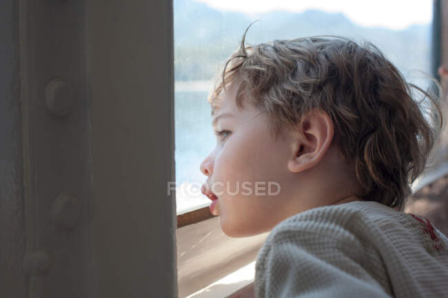 Jeune garçon regardant par la fenêtre du ferry — Photo de stock