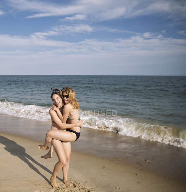 Woman carrying friend on beach, Amagansett, New York, USA — Stock Photo