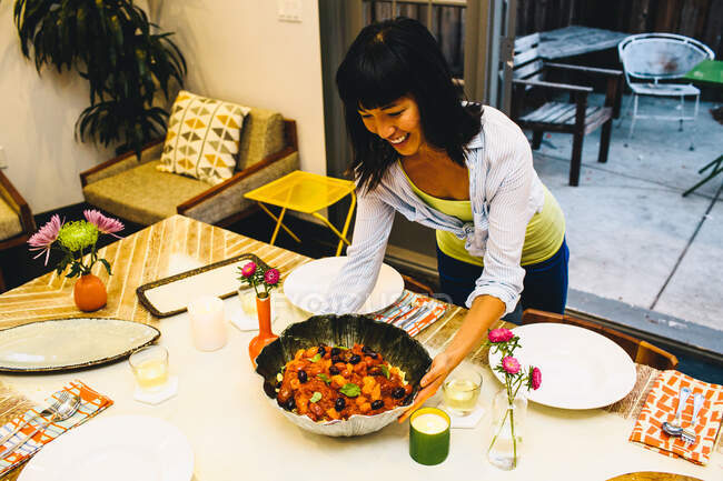 Donna che mette il piatto sul tavolo da pranzo — Foto stock