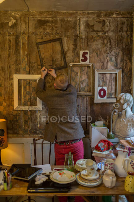 Man nailing frames to wall — Stock Photo